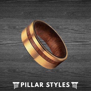 May include: A gold and brown wood ring with a brushed finish. The ring has a thin gold band with a wood inlay.