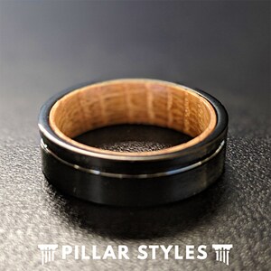May include: A black tungsten carbide ring with a wood inlay. The ring has a beveled edge and a polished finish.