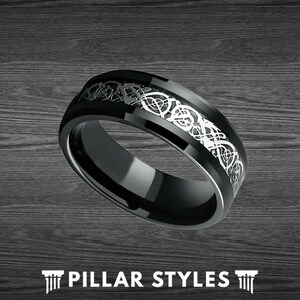 May include: A black and silver wedding band with a Celtic knot design. The band is made of tungsten carbide and has a polished finish.