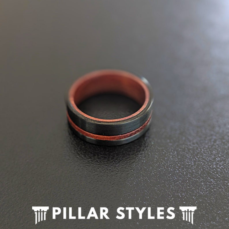 May include: A black and red ring with a wood inlay. The ring is made of a durable material and has a sleek, modern design.