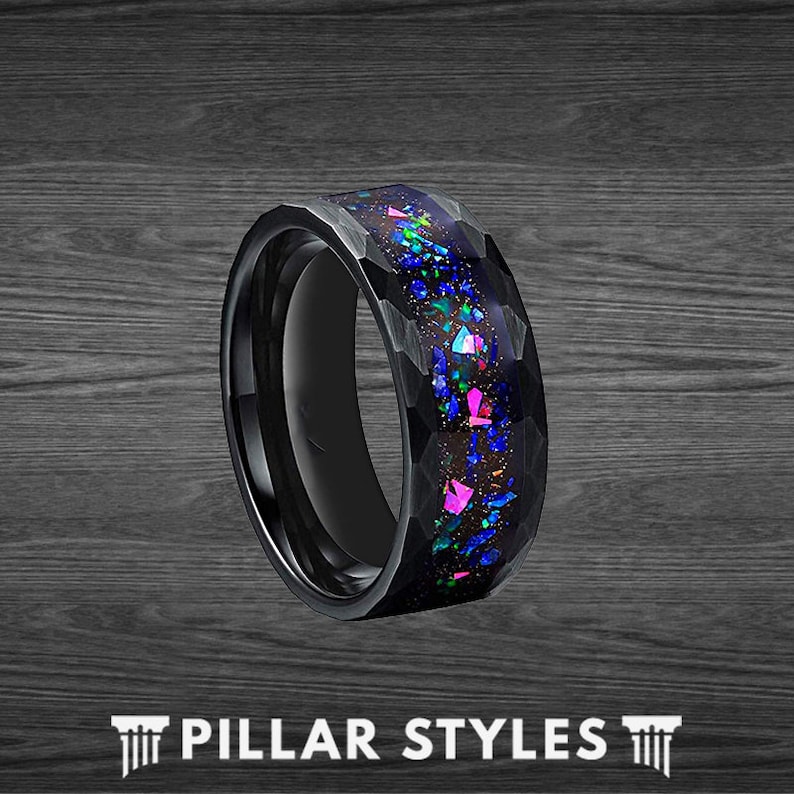 May include: A black tungsten carbide ring with a hammered finish and a blue and pink opal inlay.