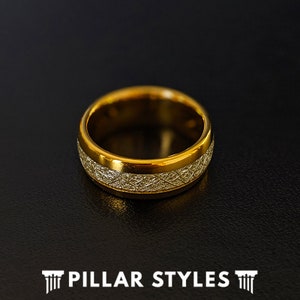 May include: A gold-toned ring with a textured band. The band has a brushed finish and a thin, polished edge.