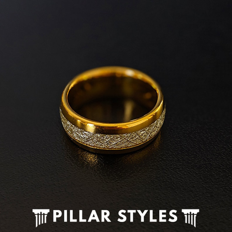 May include: A gold-toned ring with a textured band. The band has a brushed finish and a thin, polished edge.