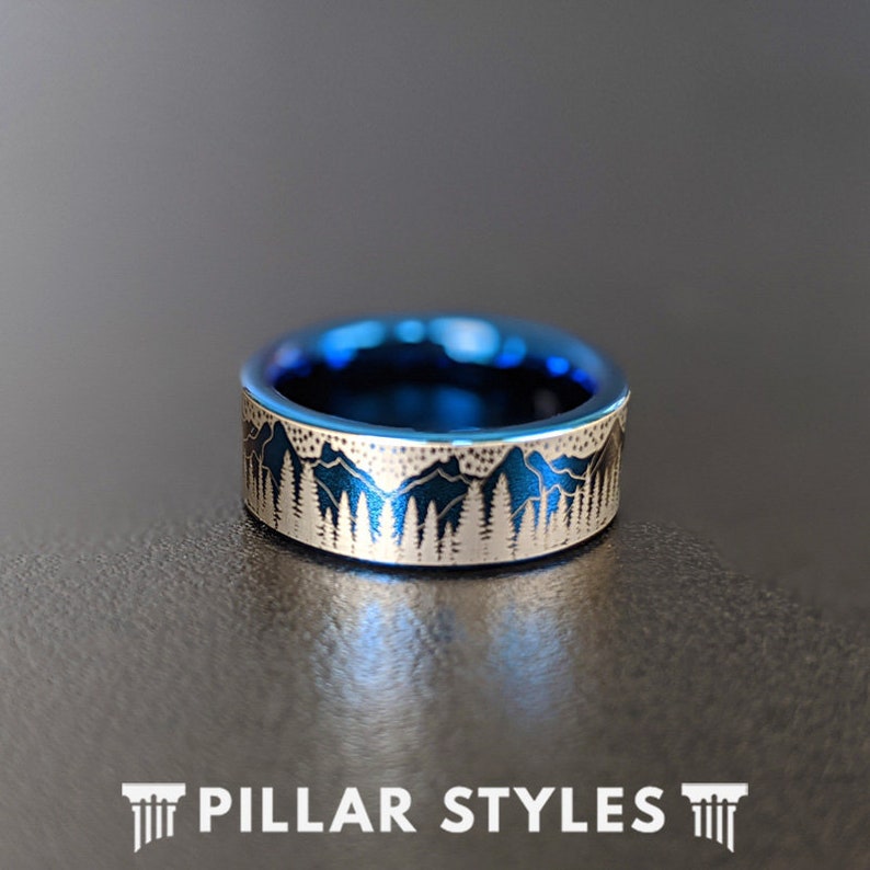 May include: A blue and silver ring with a mountain range design. The ring is made of tungsten carbide and has a polished finish.