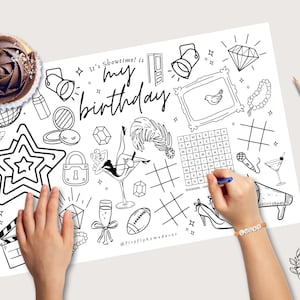 May include: A black and white birthday-themed coloring page with the text "It's Showtime! It's my birthday". Includes illustrations of a star, martini glass, high heel, and a cupcake. Colored pencils are visible.