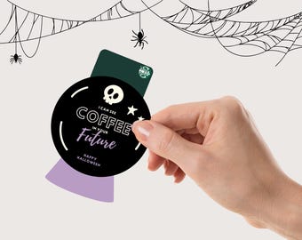 May include: A black and white Halloween-themed coffee coaster with the text "I can see coffee in your future" and "Happy Halloween". The coaster is held in front of a green Starbucks gift card. Spiderwebs and spiders are in the background.