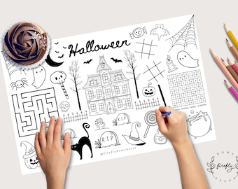 May include: Black and white Halloween-themed activity sheet with a haunted house, bats, and a word search. A cupcake with chocolate frosting sits at the top left. Colored pencils are on the right. A hand is drawing with a blue pen.