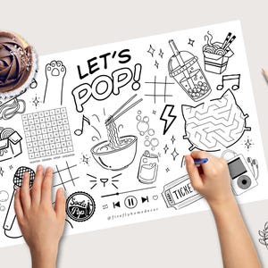 May include: A black and white doodle-style placemat featuring the words "LET'S POP!" and illustrations of ramen, boba tea, and a maze. A chocolate cupcake and coloured pencils are also present.
