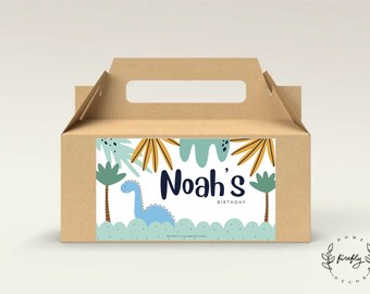 May include: A brown cardboard box with a handle, decorated with a sticker featuring a blue dinosaur, green palm trees, and the text "Noah's Birthday".