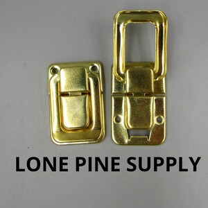 May include: Two gold-toned metal clasps with a latch and a handle. The clasps are designed to be used for securing boxes or other items.