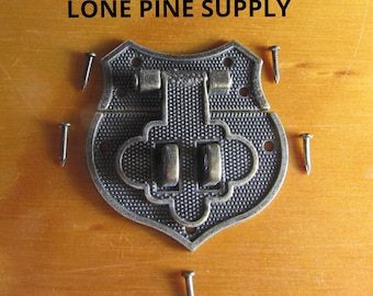 Könnte beinhalten: Antiker Messingverschluss mit dekorativem Design und fünf kleinen Nägeln. LONE PINE SUPPLY ist oben im Bild in schwarzer Schrift geschrieben.