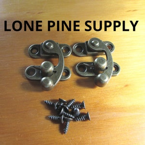 May include: Two antique brass-toned latch clasps with a rounded knob and two screw holes. The clasps are on a wooden surface with eight black screws.