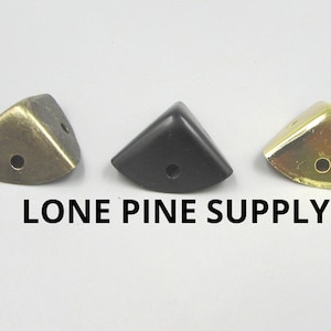 May include: Three corner protectors in different finishes: brass, black, and gold.  The corner protectors are made of metal and have a rounded edge.  LONE PINE SUPPLY is printed below the corner protectors.