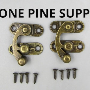 May include: Two antique brass-colored clasps with matching screws. Each clasp has a curved hook and a rounded knob. The text "LONE PINE SUPPLY" is printed in black at the top of the image.