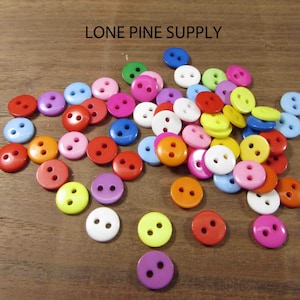 May include: A large assortment of colorful plastic buttons with two holes each. The buttons are in various shades of red, orange, yellow, green, blue, purple, pink, and white.