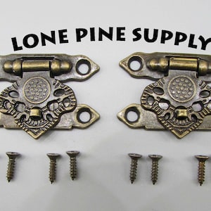 May include: Two antique brass-toned box clasps with ornate designs and a hinge. Each clasp has two holes for screws. Four screws are included.