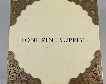 Könnte beinhalten: Eine weiße Karte mit verzierten goldenen Eckverzierungen und dem Text "LONE PINE SUPPLY" in Schwarz gedruckt.