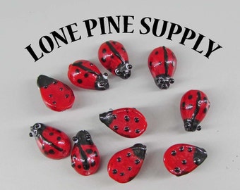 May include: Ten red and black ladybug glass beads with black dots. The beads are approximately 1 inch in size.