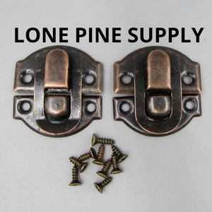May include: Two antique copper-toned metal box clasps with a rounded rectangular shape and a raised lip. Each clasp has two small holes for screws. The clasps are accompanied by eight small screws.