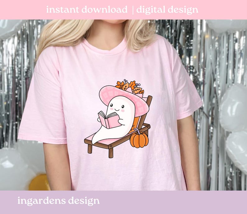May include: A light pink t-shirt featuring a cartoon ghost reading a book while relaxing on a beach chair. The ghost wears a pink hat and is surrounded by fall foliage and a pumpkin. Text at the top reads "instant download | digital design."