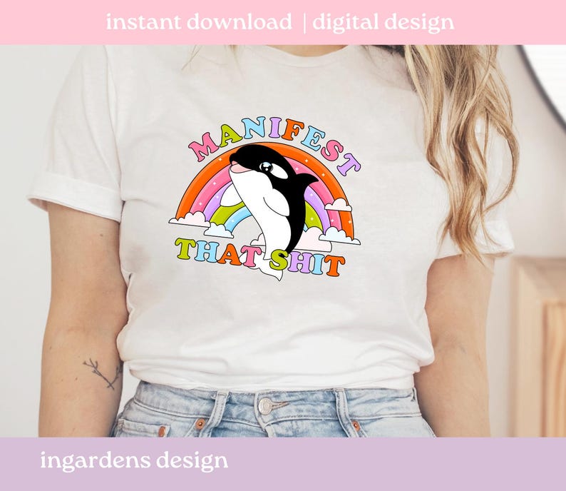 K&ouml;nnte beinhalten: Wei&szlig;es T-Shirt mit einem Cartoon-Orca-Wal-Design, einem Regenbogen und dem Text "MANIFEST THAT SHIT". Das Design verwendet helle Farben. Das T-Shirt hat einen l&auml;ssigen Stil.