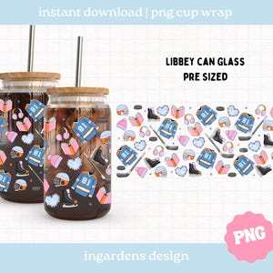 Puede incluir: Dos vasos de vidrio Libbey con tapas de madera y pajitas de metal. Los vasos están llenos de un líquido oscuro y decorados con un patrón de temática de hockey que incluye camisetas, patines y cascos. El texto "LIBBEY CAN GLASS PRE SIZED" es visible.
