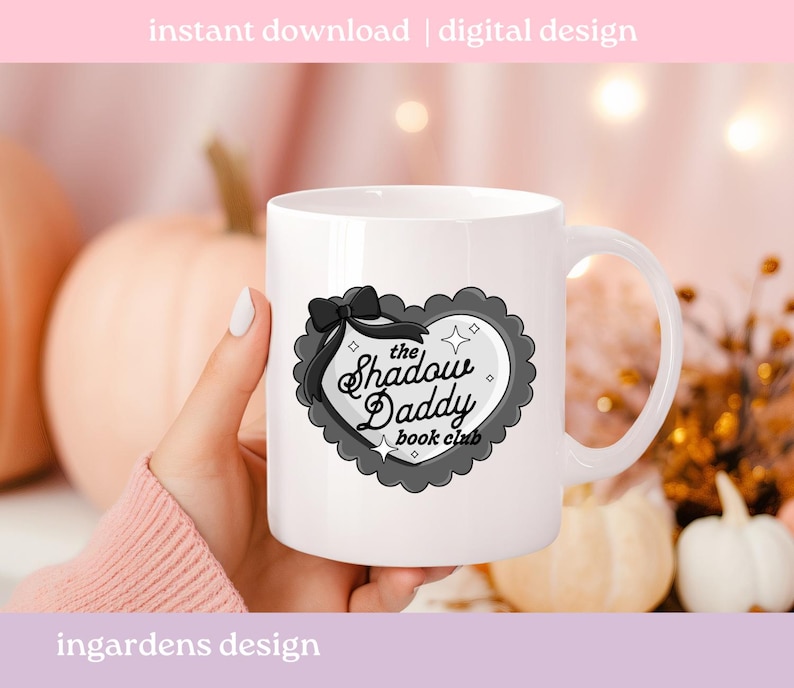 May include: White ceramic mug featuring a heart-shaped design with the text "The Shadow Daddy book club". The design includes a black bow and a gray scalloped border. The words "instant download | digital design" and "ingardens design" are also visible.