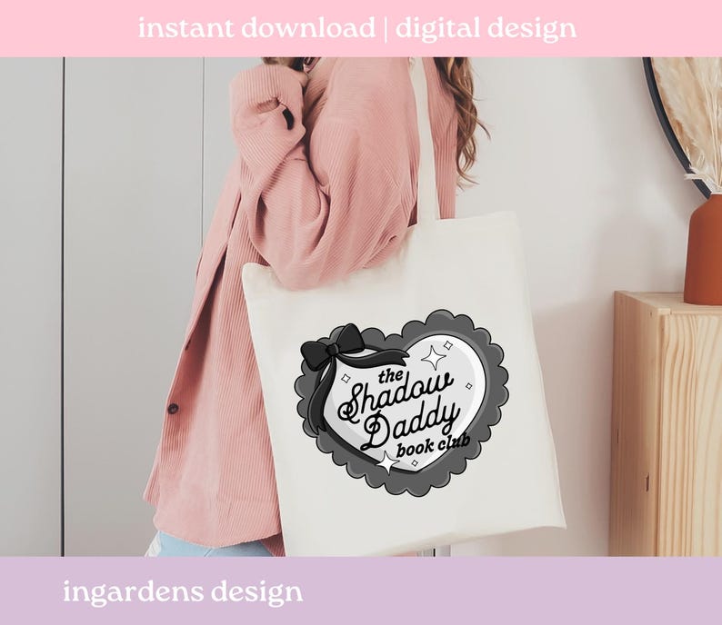 May include: A white tote bag featuring a black and gray heart-shaped design with a bow and the text "the Shadow Daddy book club." The bag has a simple design with the words "instant download | digital design" and "ingardens design" printed on it.