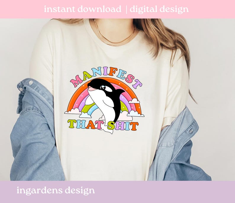 K&ouml;nnte beinhalten: Cremefarbenes T-Shirt mit einer Grafik eines schwarz-wei&szlig;en Orcas, der &uuml;ber einen Regenbogen springt. Der Text "MANIFEST THAT SHIT" ist in bunten Buchstaben &uuml;ber dem Orca angeordnet. Die Worte "sofortiger Download | digitales Design" stehen oben.