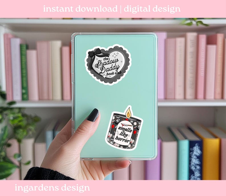 May include: A teal tablet case with two stickers: one heart-shaped with "The Shadow Daddy book club" text, and another of a candle with "smells like horror" text. The background includes a bookshelf with pink and white books.