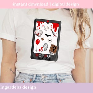 May include: White t-shirt with a black tablet design showcasing horror-themed illustrations. The tablet includes a red heart, blood drips, a knife, a skull, a coffin, a book, a bat, a balloon, and the text "HORROR Book Club".