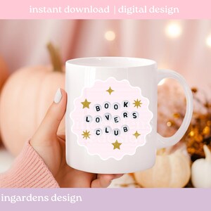 Pu&ograve; includere: Tazza in ceramica bianca con un design rosa smerlato che recita "BOOK LOVERS CLUB" in lettere nere. Stelle dorate e scoppi di stelle accentuano il design. La tazza &egrave; posta su uno sfondo sfocato.
