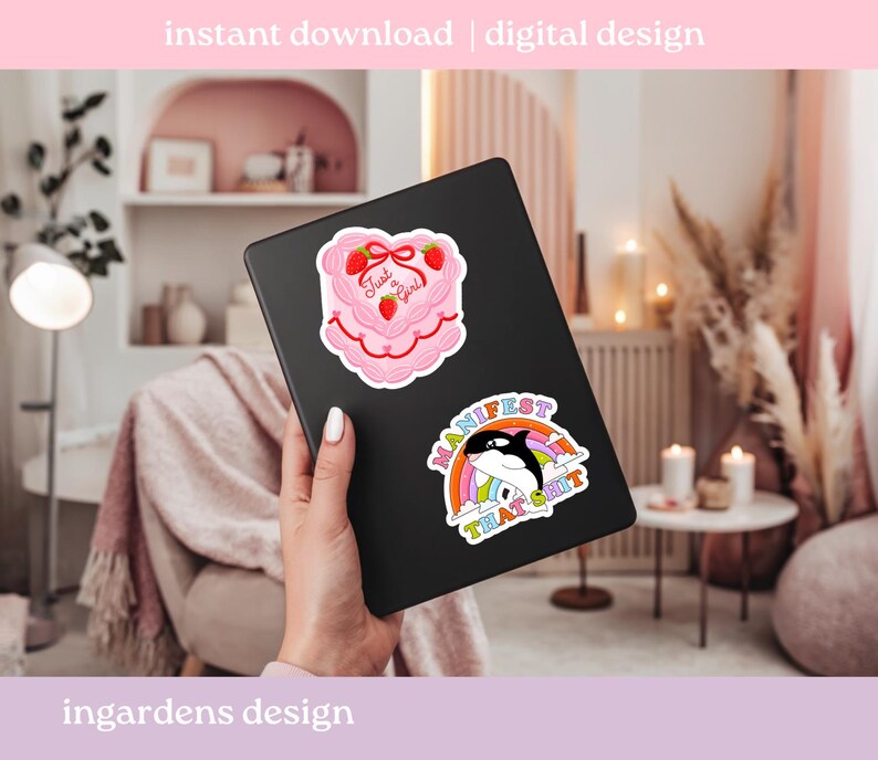 K&ouml;nnte beinhalten: Ein schwarzes Tablet mit zwei Aufklebern. Einer ist ein rosa Kuchen mit Erdbeeren und dem Text "Just a Girl". Der andere ist ein Regenbogen mit einem Wal und dem Text "Manifest That Shit".