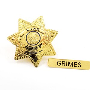 May include: Gold sheriff's star badge with the words "King County Sheriff" and a name tag that reads "Grimes".