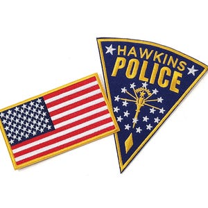 May include: A rectangular embroidered patch featuring the United States flag with red, white, and blue colors, alongside a triangular dark blue embroidered patch with yellow text reading HAWKINS POLICE and a white star-filled Indiana state emblem.