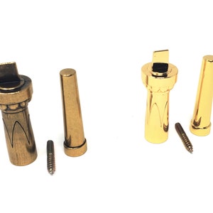 May include: Two sets of decorative door hardware, each set includes a gold-toned knob and a matching cylindrical piece. One set is a darker brass color, the other is a brighter gold. Each set includes a small screw.