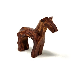 May include: A wooden horse figurine with a brown finish. The horse is standing on all four legs and has a simple, stylized design.