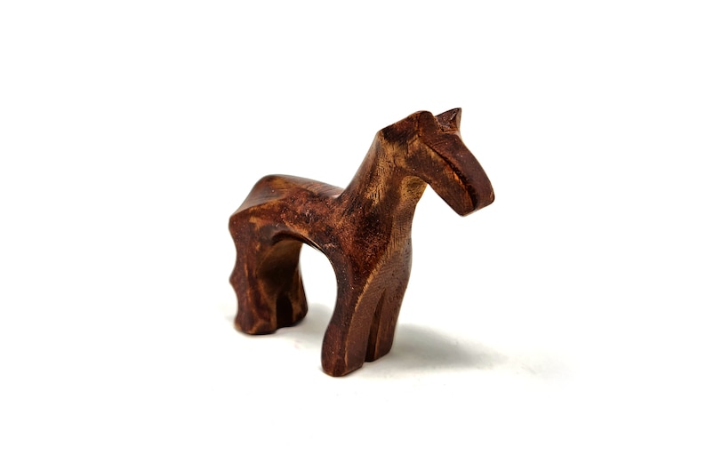 May include: A wooden horse figurine with a brown finish. The horse is standing on all four legs and has a simple, stylized design.