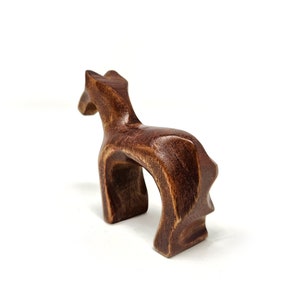 May include: A wooden horse figurine with a dark brown finish. The horse is standing on all four legs and has a simple, abstract design.