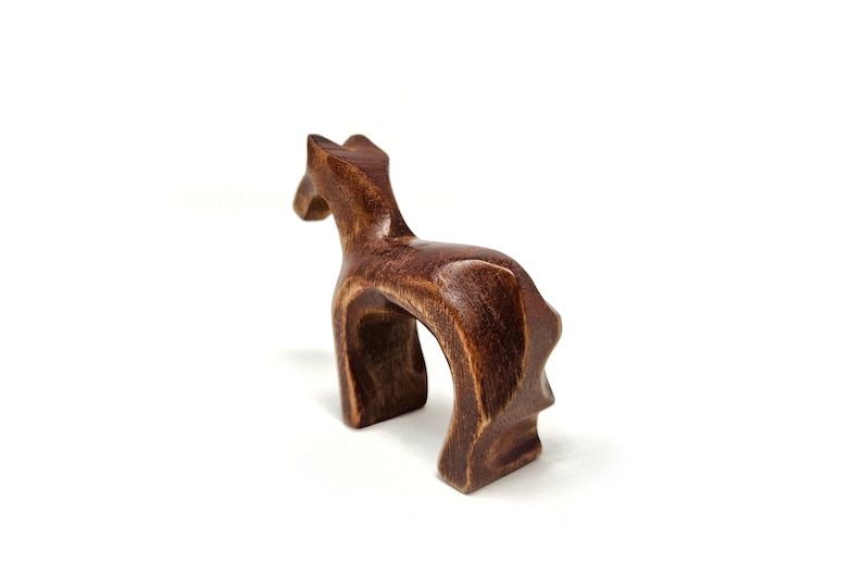 May include: A wooden horse figurine with a dark brown finish. The horse is standing on all four legs and has a simple, abstract design.