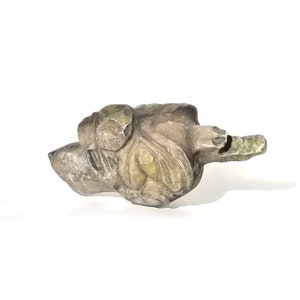 May include: A small, carved stone sculpture of a bird with green and gray accents. The bird is in a resting position with its wings folded.