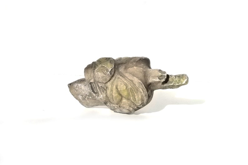May include: A small, carved stone sculpture of a bird with green and gray accents. The bird is in a resting position with its wings folded.
