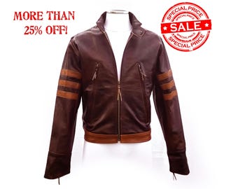 May include: A brown leather jacket with tan stripes on the sleeves and a zip closure. The jacket has a stand-up collar and two zipped pockets. The text "MORE THAN 25% OFF!" and a "SALE" stamp are visible.