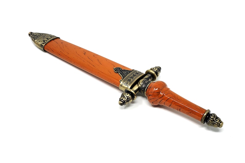 May include: A decorative dagger with an ornate metal handle and a brown wooden shaft.