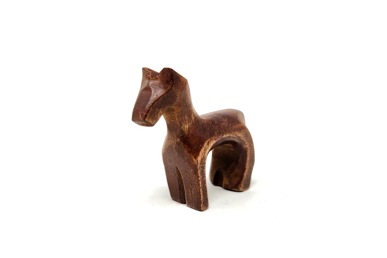 May include: A wooden horse figurine with a dark brown finish. The horse is standing on all four legs and has a simple, stylized design.