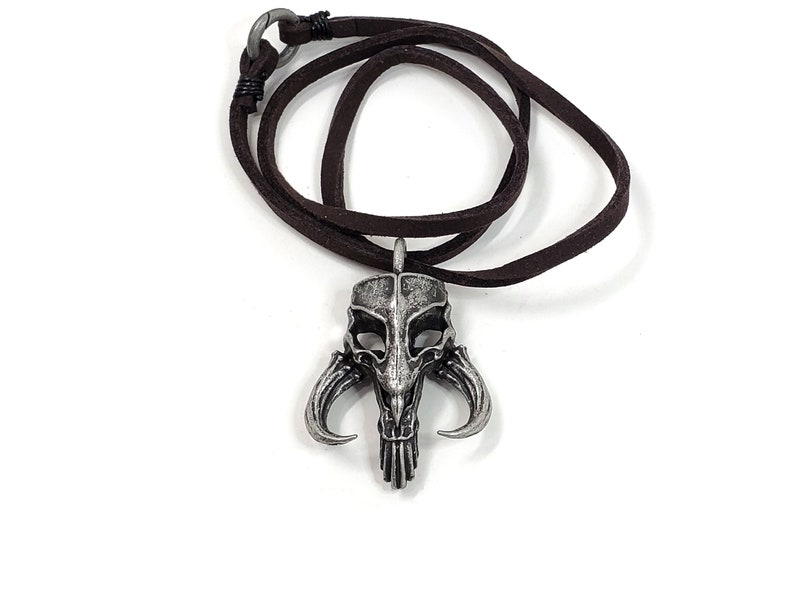 May include: A silver Mandalorian symbol pendant necklace with a brown leather cord.