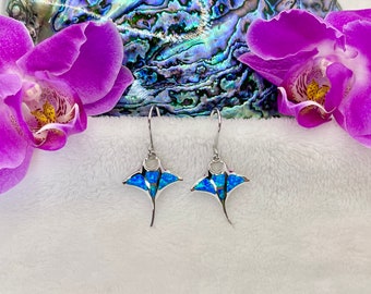 Könnte beinhalten: Ein Paar Ohrringe aus Sterlingsilber mit einem Design aus blauer Opal-Manta-Rochen. Die Ohrringe hängen an einer weißen, flauschigen Oberfläche.
