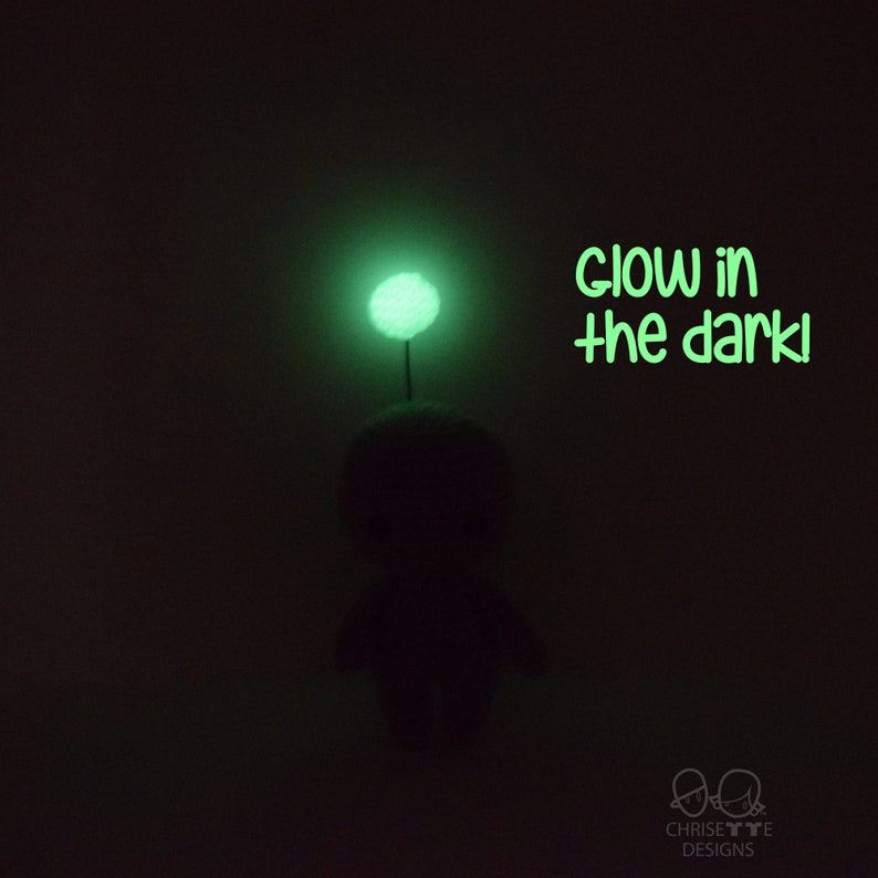 May include: A small, green, glow-in-the-dark plush toy with a round head and a small, green, glow-in-the-dark ball on top. The text "glow in the dark!" is written in green below the toy.
