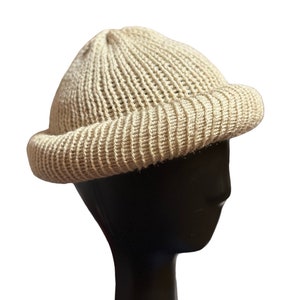 May include: A beige knitted beanie with a wide brim. The beanie is made of a soft, textured yarn.