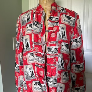 May include: A red, long-sleeved shirt with a mandarin collar and frog closures. The shirt features a repeating pattern of black and white landscape scenes and Chinese characters on a red background. The shirt is displayed on a mannequin.